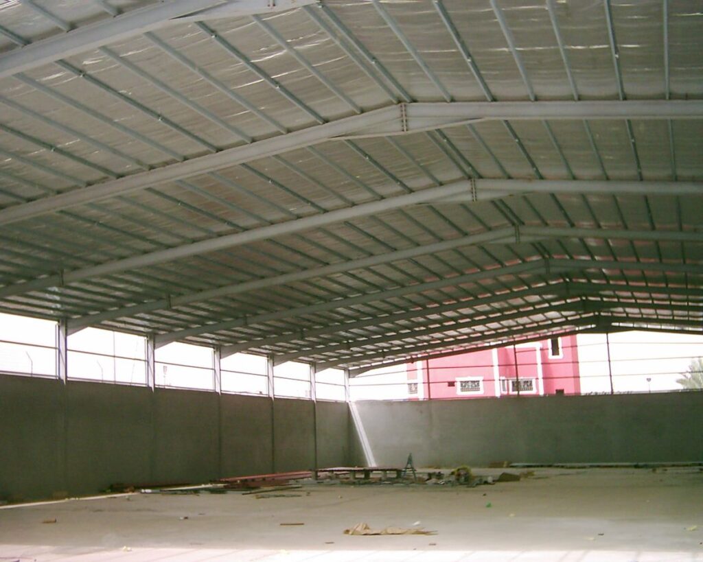 منظر داخلي لهنجر واسع في الرياض، يظهر السقف وقد تم تغطيته وعزله بمادة فضية عاكسة. الجدران الجانبية خرسانية، وهناك شريط من النوافذ العلوية لإدخال الضوء الطبيعي، والأرضية خرسانية وواسعة.